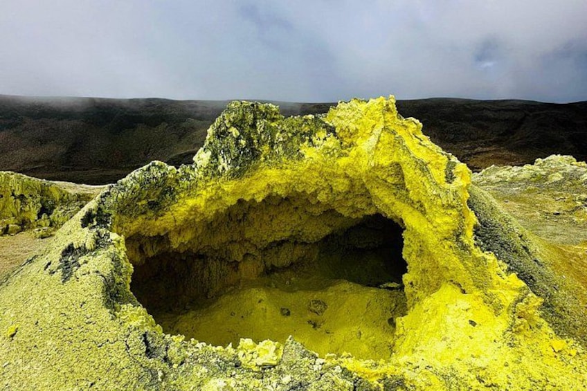 A large cave opening with yellow mineral deposits. 2