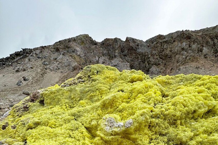 A yellow moss-covered rock formation with a rugged, rocky background. 3