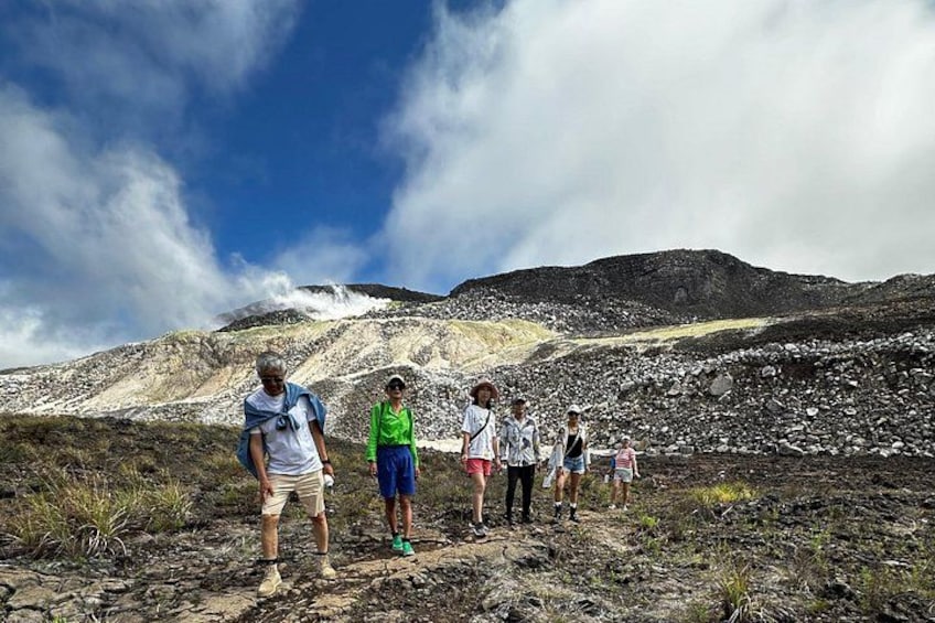 A group of people hiking on a rocky trail with a mountainous landscape in the background. 4