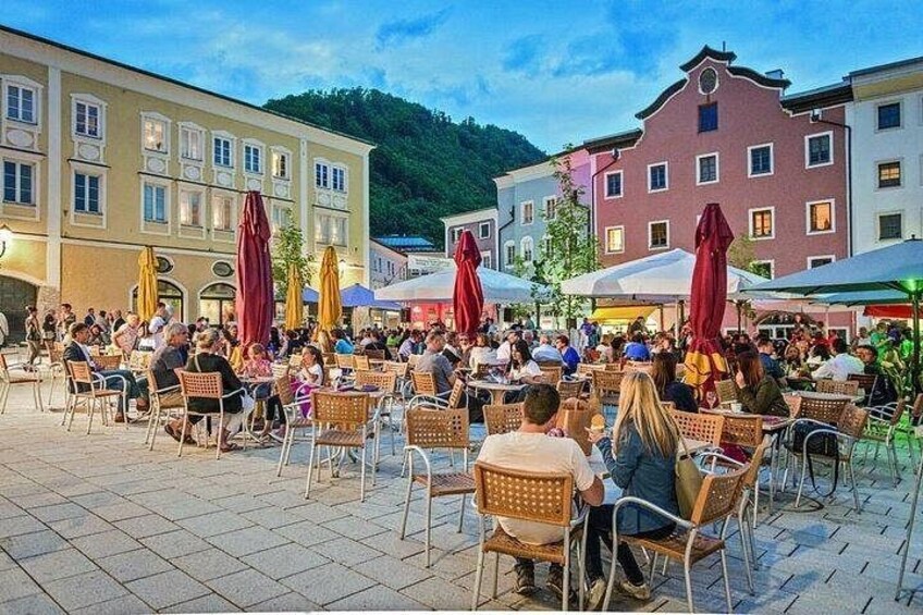 An outdoor café with people dining, surrounded by buildings and trees. 2