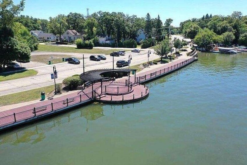 A waterfront area with a pedestrian bridge, a parking lot, and a road. 5