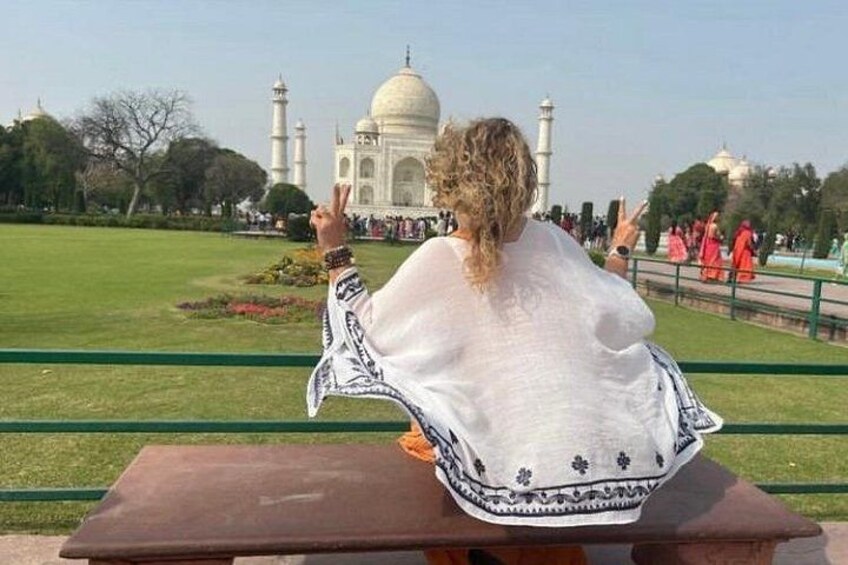 A person sitting on a bench facing the Taj Mahal. 1