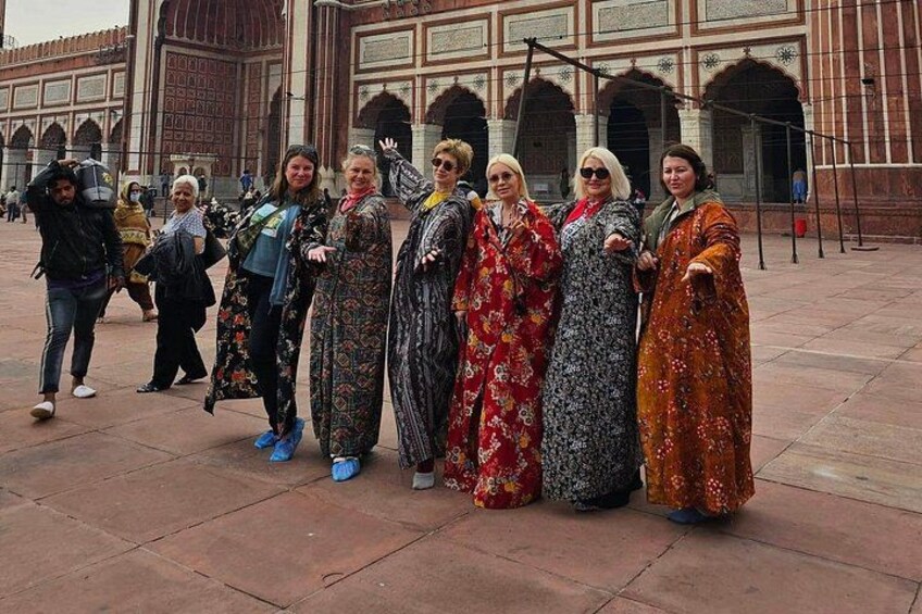 A group of people in traditional attire standing in front of a historic building with arches. 3