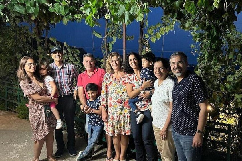 Un gruppo di persone in piedi sotto un albero, con un muro blu sullo sfondo. 5