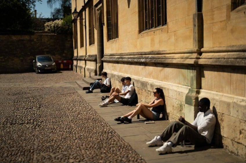 People sitting on a sidewalk next to a building. 3
