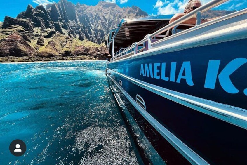 A boat named 'AMELIA' on a turquoise body of water with rocky mountains in the background. 3