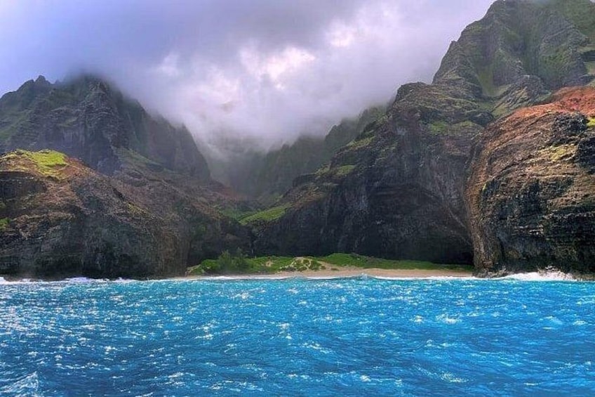 Een kustlandschap met een heldere blauwe zee, rotsachtige kliffen en een smalle doorgang tussen de kliffen. 3
