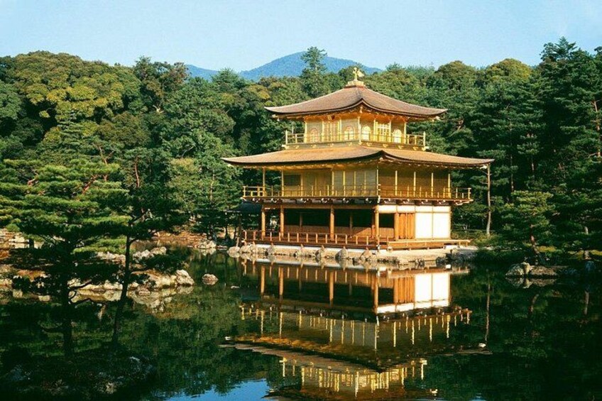 A traditional Japanese pagoda with a reflection in a calm pond, surrounded by lush greenery and hills. 1