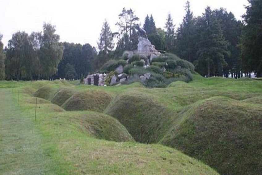 A grassy field with a mound and a stone structure. 5