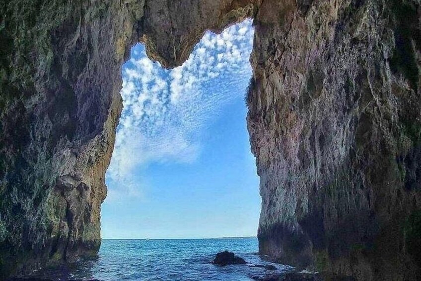 A natural rock formation with a clear view of the ocean through a cave-like opening. 1