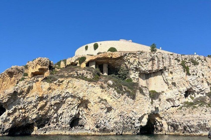 A historic building on a rocky cliff with a clear blue sky. 3