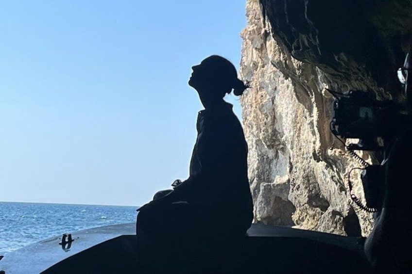 A person sitting on a rock by the sea, overlooking the ocean. 1