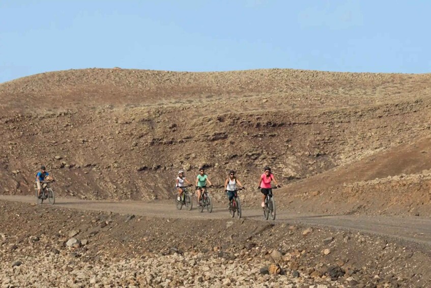 A group of cyclists on a dirt road in a hilly, rocky landscape. 5