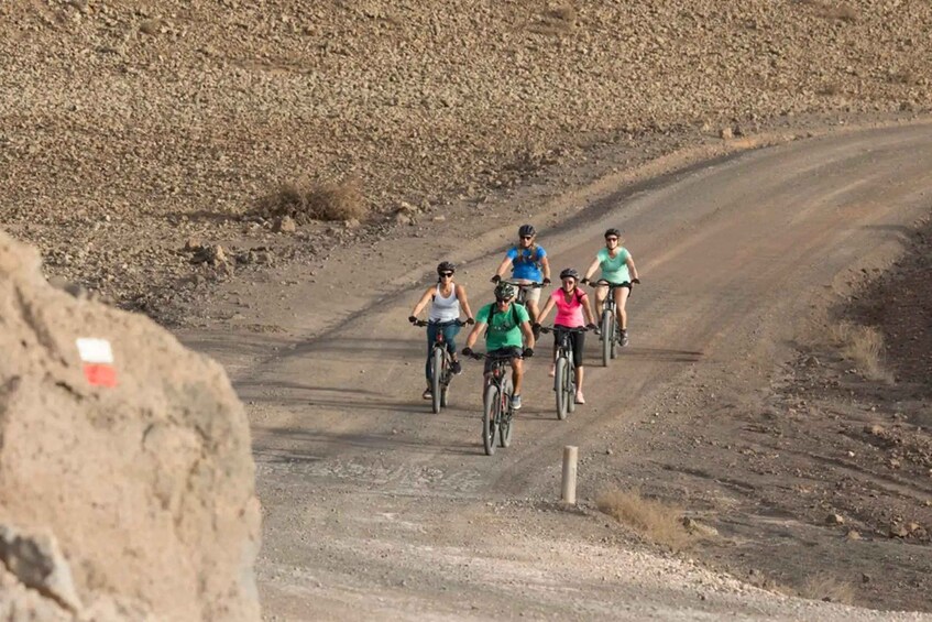 A group of cyclists on a dirt road in a dry, rocky landscape. 4