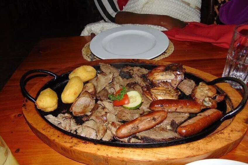 Una sartén grande con diferentes carnes y verduras sobre una mesa de madera. 3