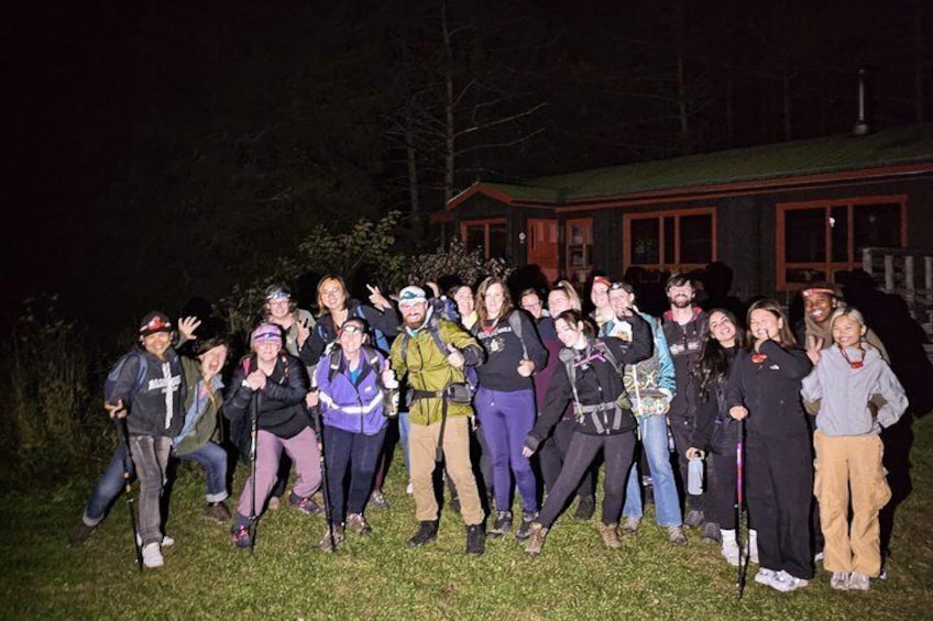A group of people posing in front of a building at night. 3