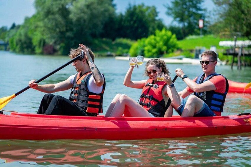 Tres personas en un canoa roja sobre aguas tranquilas, usando chalecos salvavidas. 1
