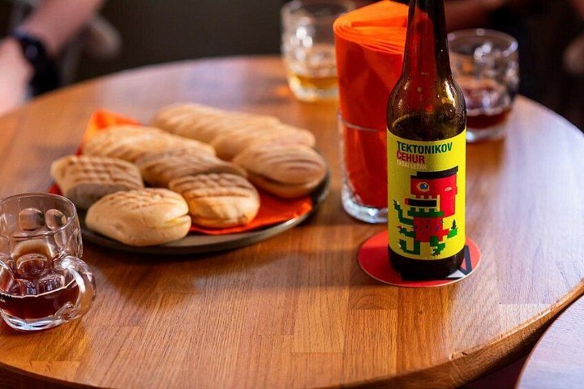 Una botella de cerveza Tektonikov, un plato de galletas y vasos sobre una mesa de madera. 2