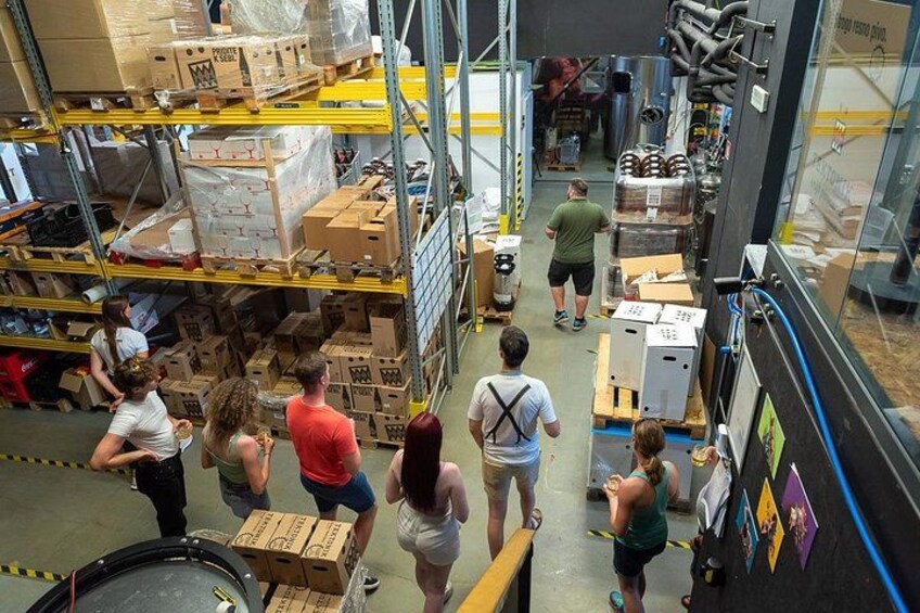 Un almacén con gente trabajando, estanterías llenas de cajas y una carretilla elevadora al frente. 3