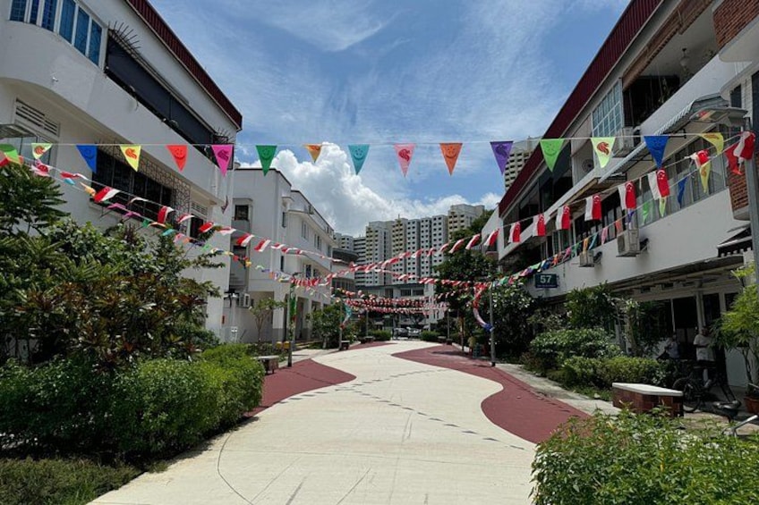 A street with buildings, a sidewalk, and colorful flags. 3