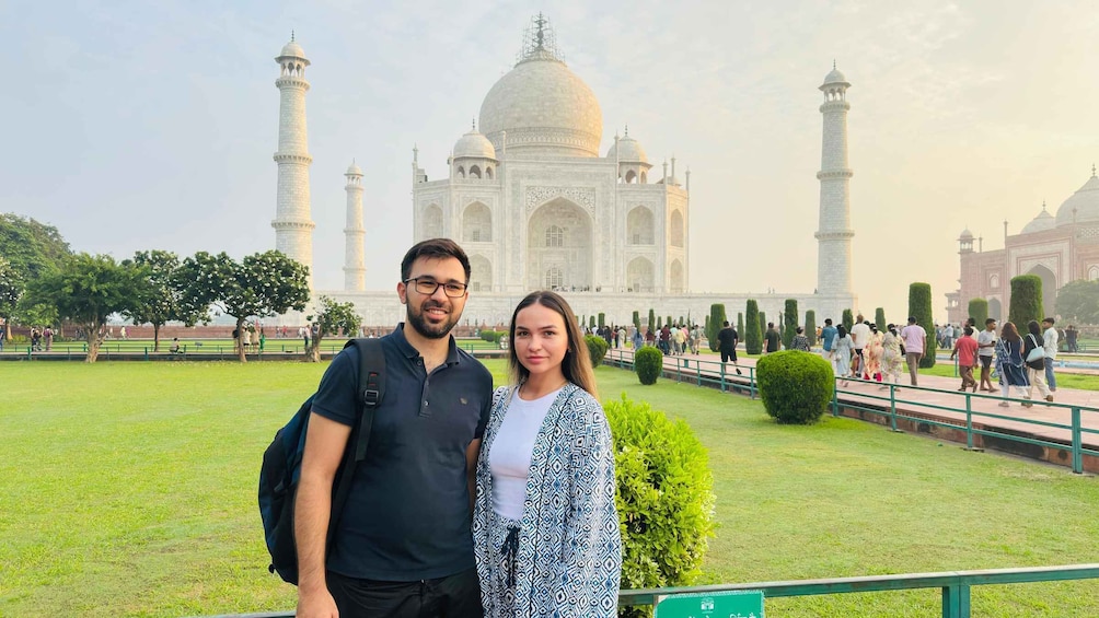 A couple standing in front of the Taj Mahal with its iconic domes and minarets. 3