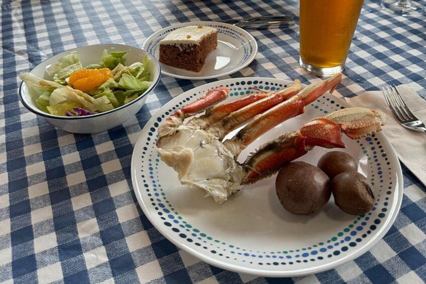 A meal with lobster, salad, cake, and a glass of beer on a checkered tablecloth. 2
