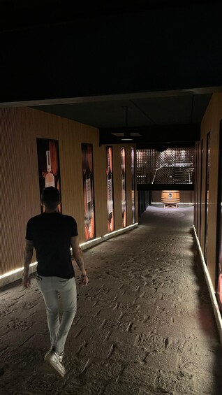 A person walking down a dimly lit corridor with patterned walls and a tiled floor. 5