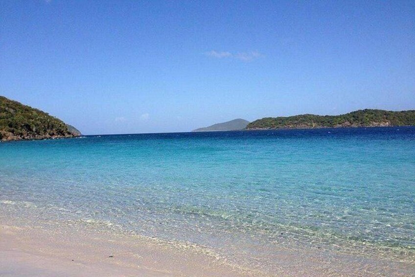 A clear blue sea, sandy beach, and green hills. 3