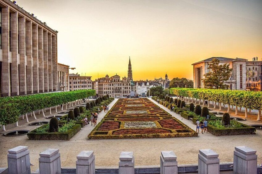 A formal garden with geometrically arranged flower beds, a central fountain, and classical architecture in the background. 1