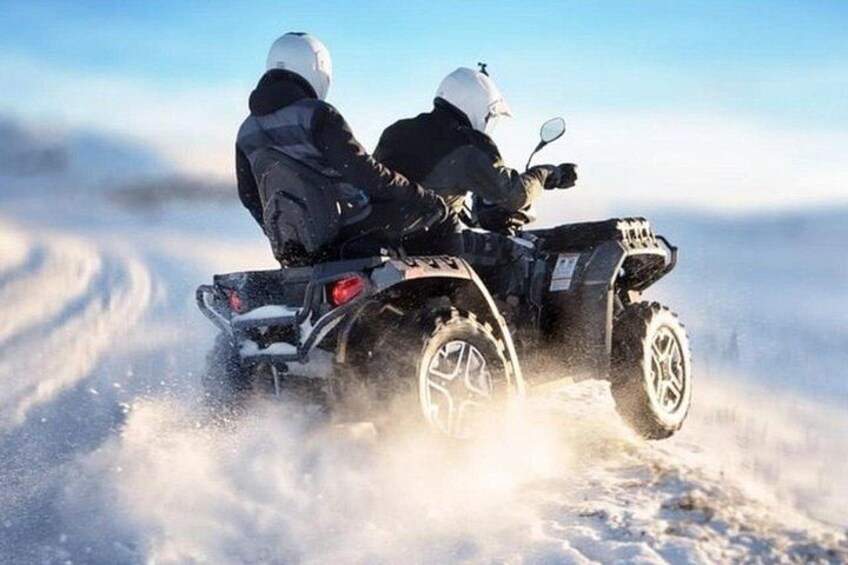 Two people on a snowmobile in a snowy landscape. 5