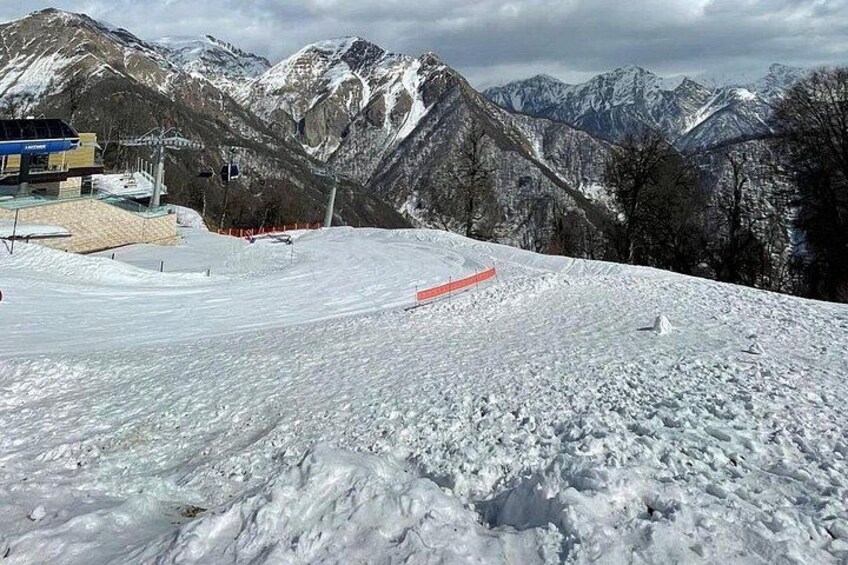 A snowy mountain landscape with ski slopes, a ski lift, and a building. 2