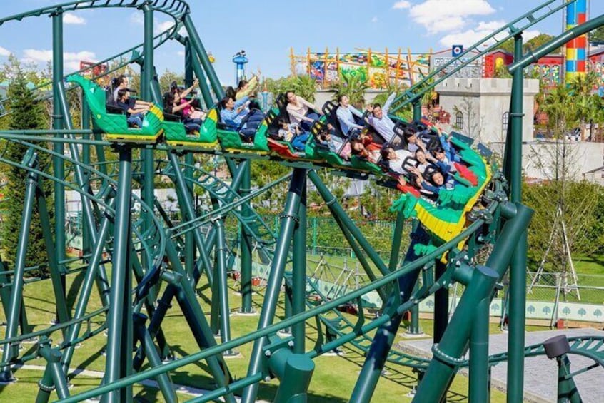 A roller coaster with passengers in green cars. 2