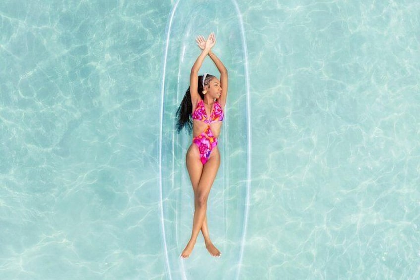 A person floating on a clear blue water surface. 4