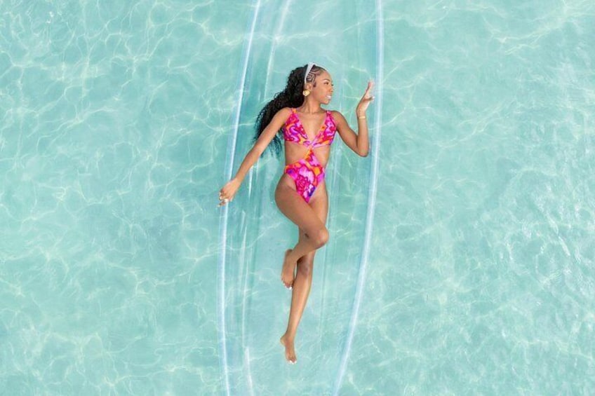 A person floating on a clear blue water surface. 3