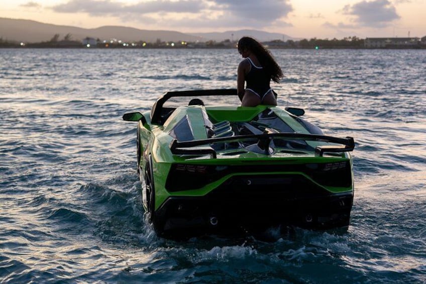 Ein grüner Sportwagen auf dem Wasser, eine Person sitzt auf dem Dach. 3