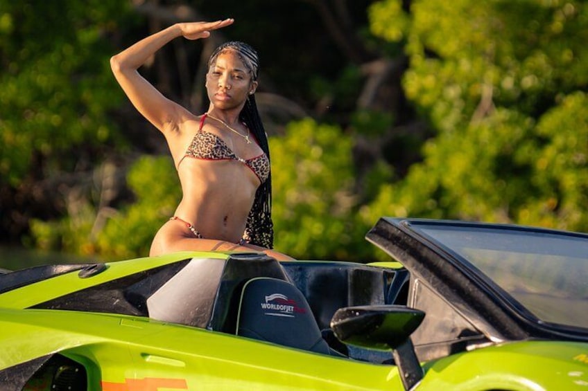 Eine Person in einem Bikini sitzt auf einem grünen Sportwagen mit dem 'WORLDJET'-Logo. 5