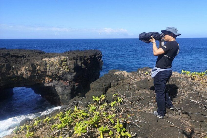 Una persona fotografiando una costa rocosa con un cielo azul despejado. 5