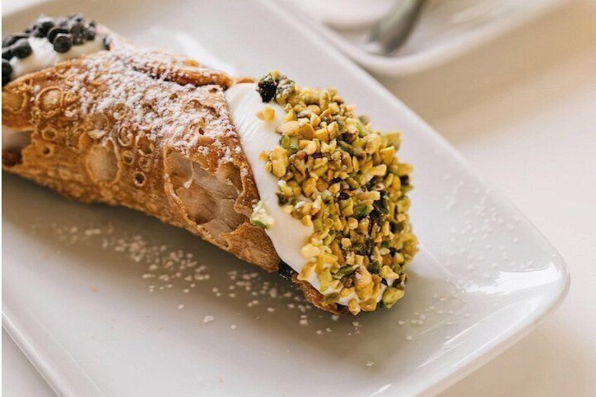 A cannoli with a creamy filling and a dusting of crushed pistachios. 5