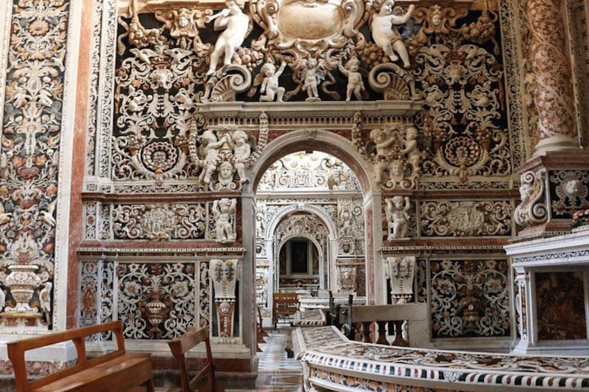 Una habitación ornamentada con detalles intrincados en las paredes y el techo, un banco de madera y un suelo con diseño. 5
