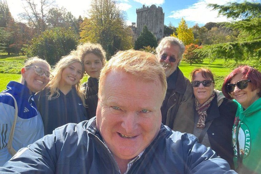 Un groupe de personnes se trouve dans un parc, avec un château en arrière-plan. 4