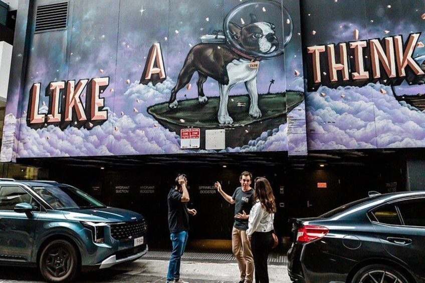 Une rue où l’on peut voir une grande affiche publicitaire représentant un chien et sur laquelle est écrit : « PENSE COMME UN CHIEN ». 4