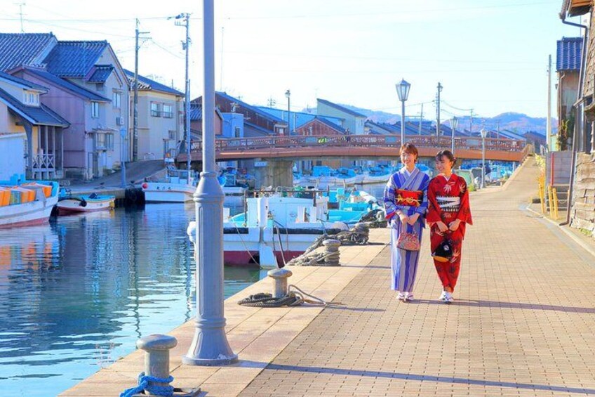 Une promenade en bord de mer avec des bateaux amarrés, un sentier piétonnier et des bâtiments traditionnels japonais. 1