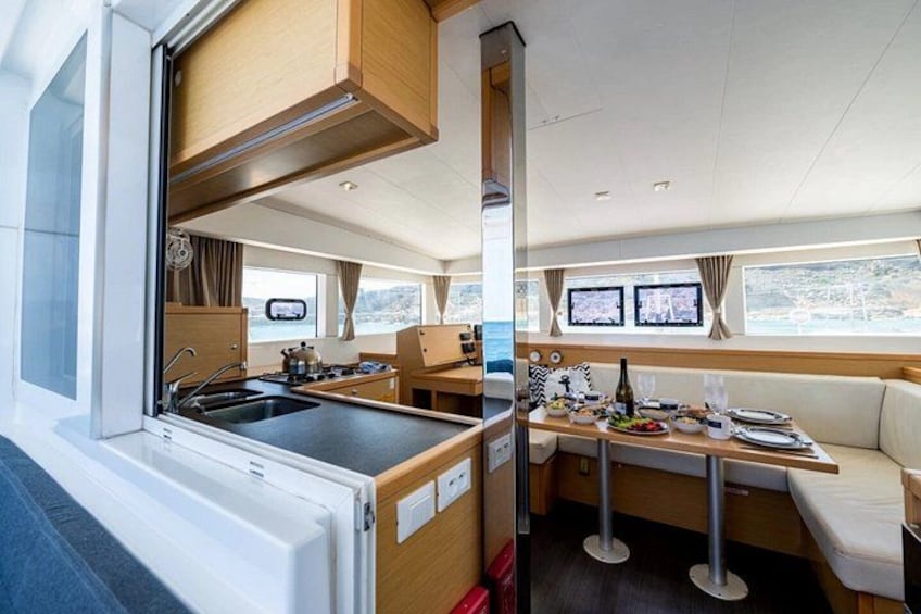 A compact kitchen with a stove, sink, and dining area on a boat. 4