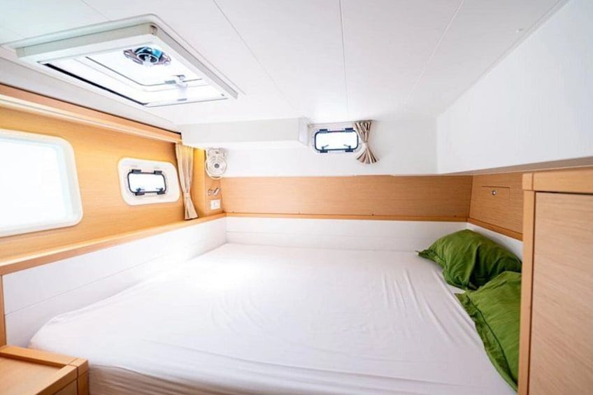 A compact, well-lit cabin with a single bed, a small window, and a ceiling light fixture. 5