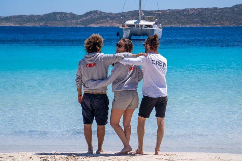 Tre personer står på en strand med en båt i bakgrunden. 5