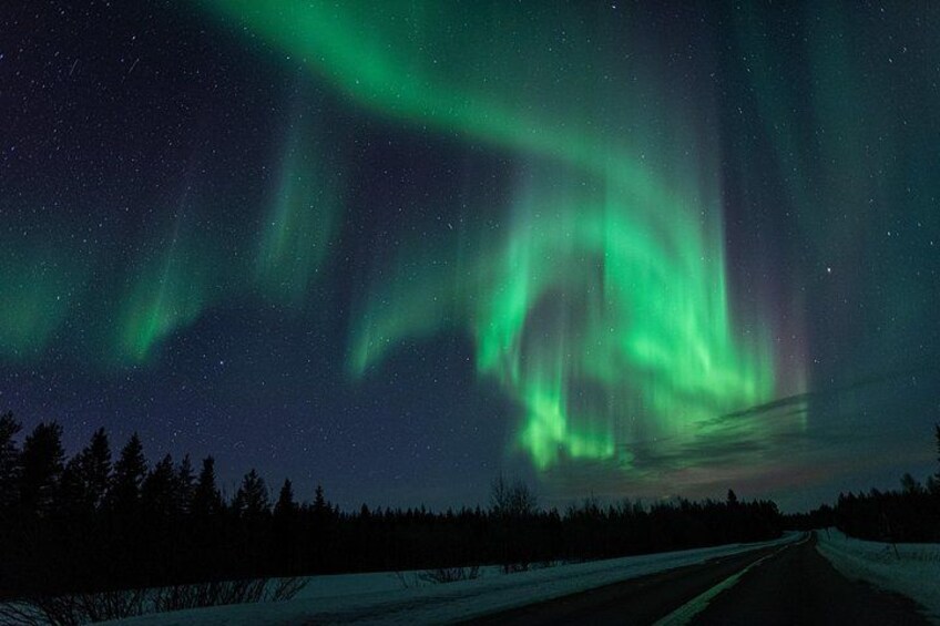 Las auroras boreales sobre un paisaje nevado con una carretera. 4