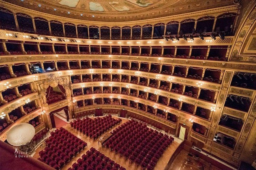 A grand theater with multiple balconies and rows of red seats. 5