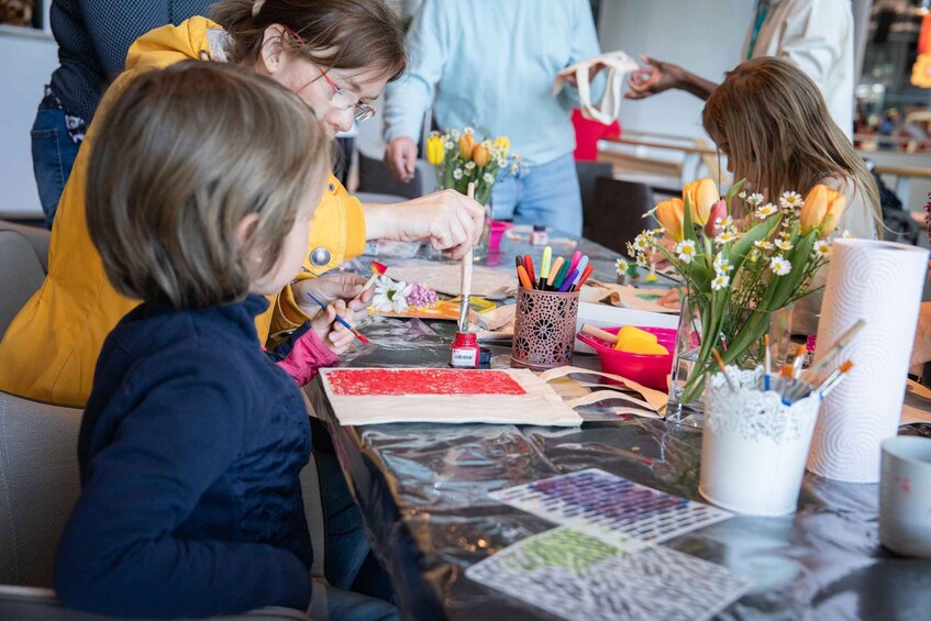 Children engaged in a painting activity with various art supplies on a table. 3