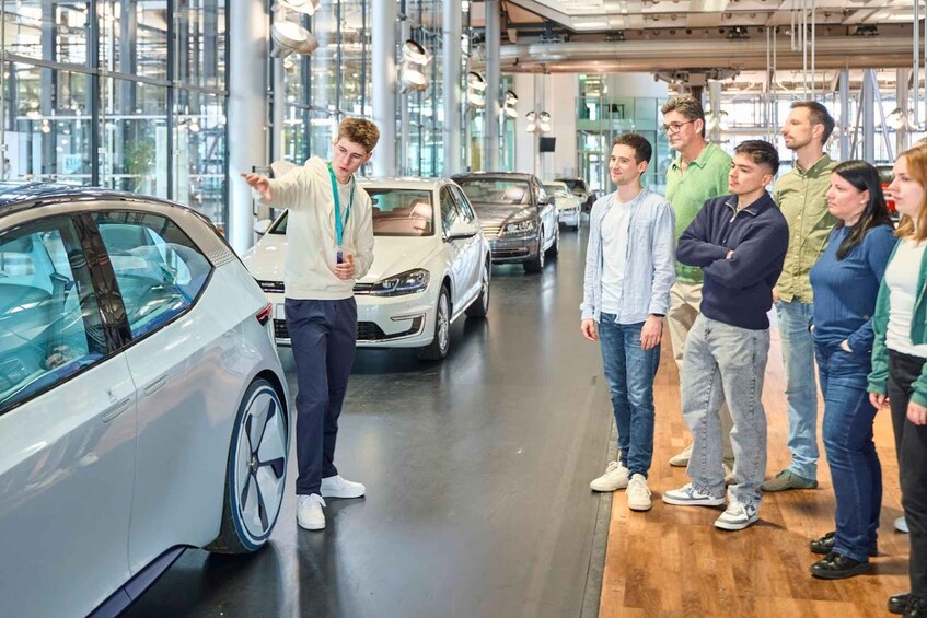 A group of people in a car showroom with a white car being presented. 2