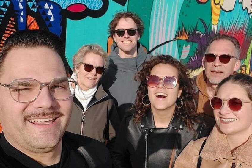 A group of people in front of a colorful mural. 2